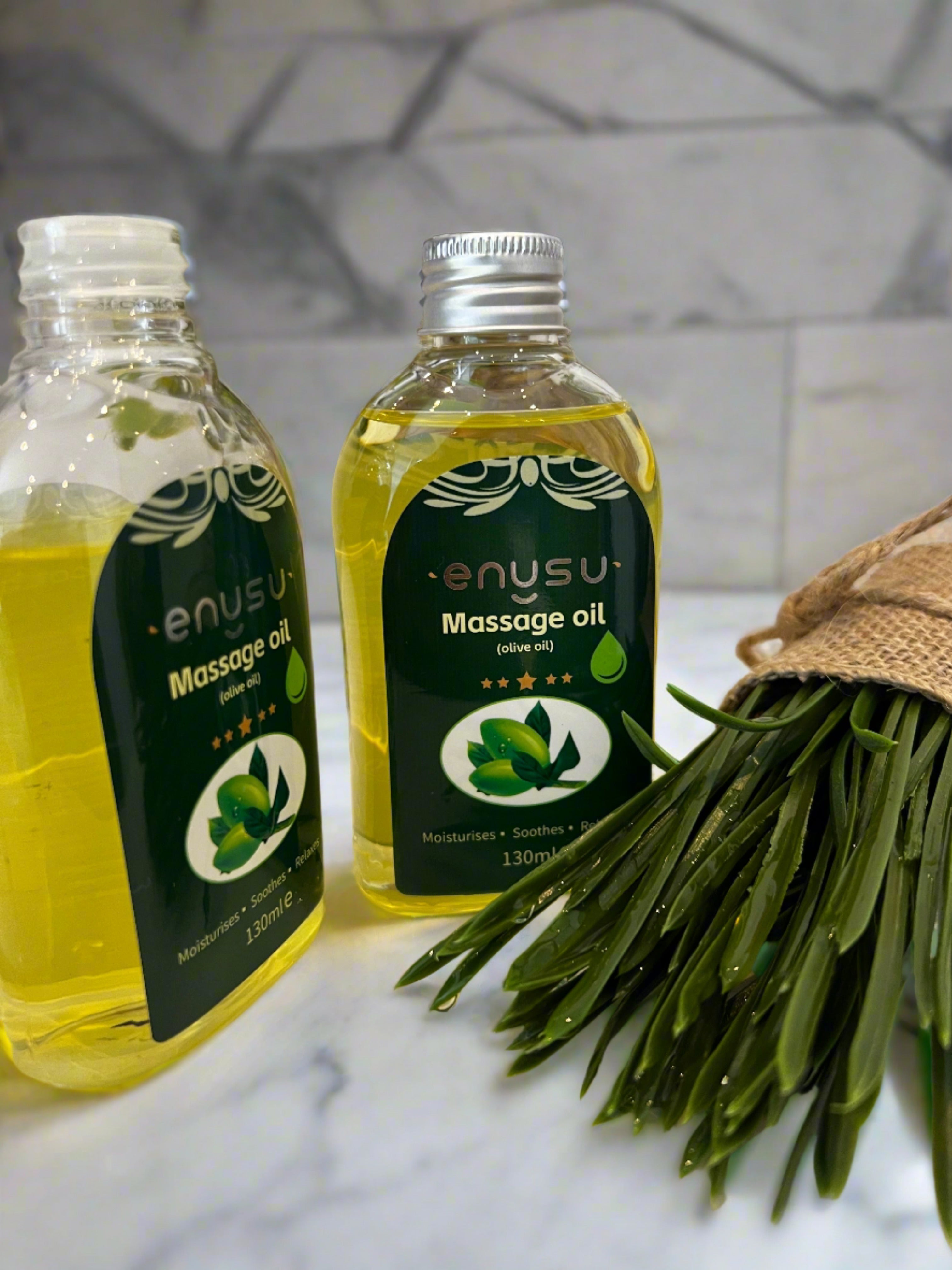 a couple of bottles of olive  massage oil next to a plant